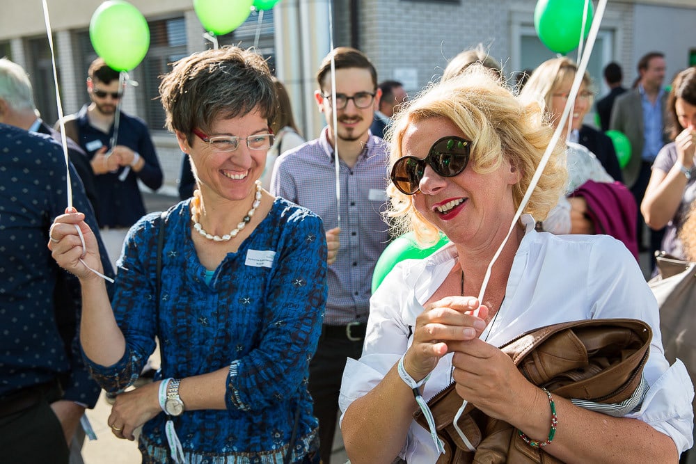 zwei fröhliche Frauen mit grünen Luftballons.